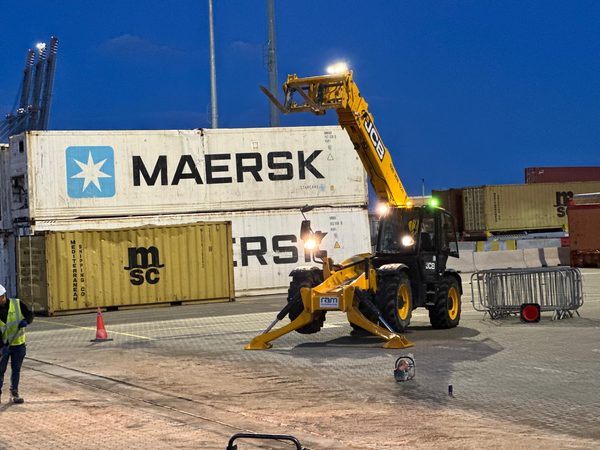 JCB operating at night near Maersk containers